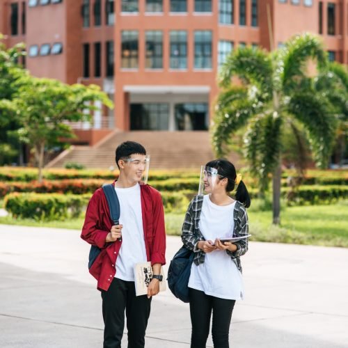 Male and female students wear a face Chill and stand in front of the university.